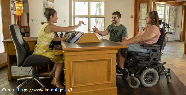 Personne qui tend un billet d'accès à 2 autres personnes, dont une en fauteuil roulant.