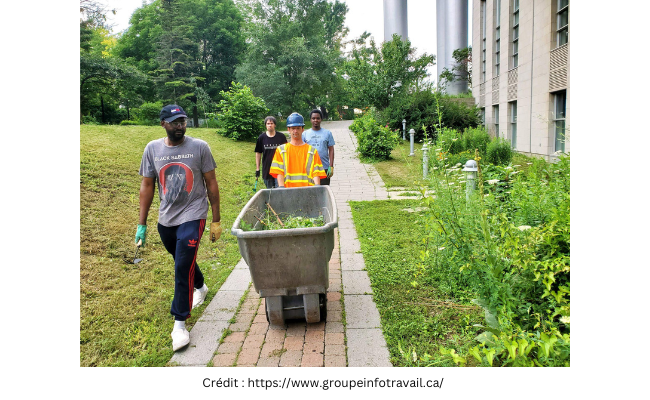 4 personnes racisées avancent sur un chemin entouré de verdure. Un homme transporte une brouette avec des déchets verts