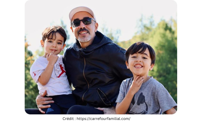 deux petits garçons dans les bras de leur père au milieu qui sourient
