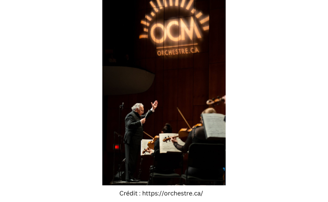 Un chef d'orchestre devant ses musiciens avec le logo de l'orchestre classique de Montréal lumineux au-dessus